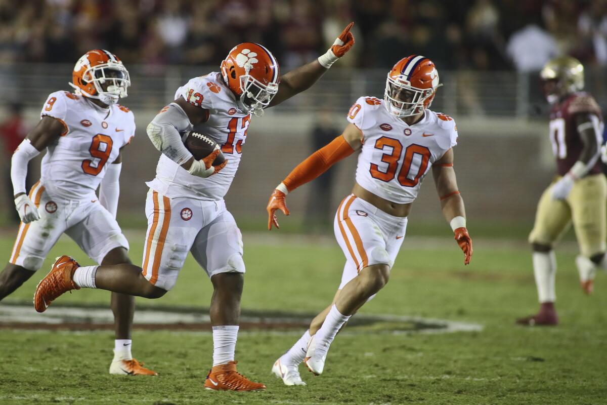 Clemson defensive tackle Tyler Davis (13) celebrates his fumble recovery with safety R.J. Mickens (9) and linebacker Keith Maguire (30) during the second quarter of the team's NCAA college football game against Florida State on Saturday, Oct. 15, 2022, in Tallahassee, Fla. (AP Photo/Phil Sears)