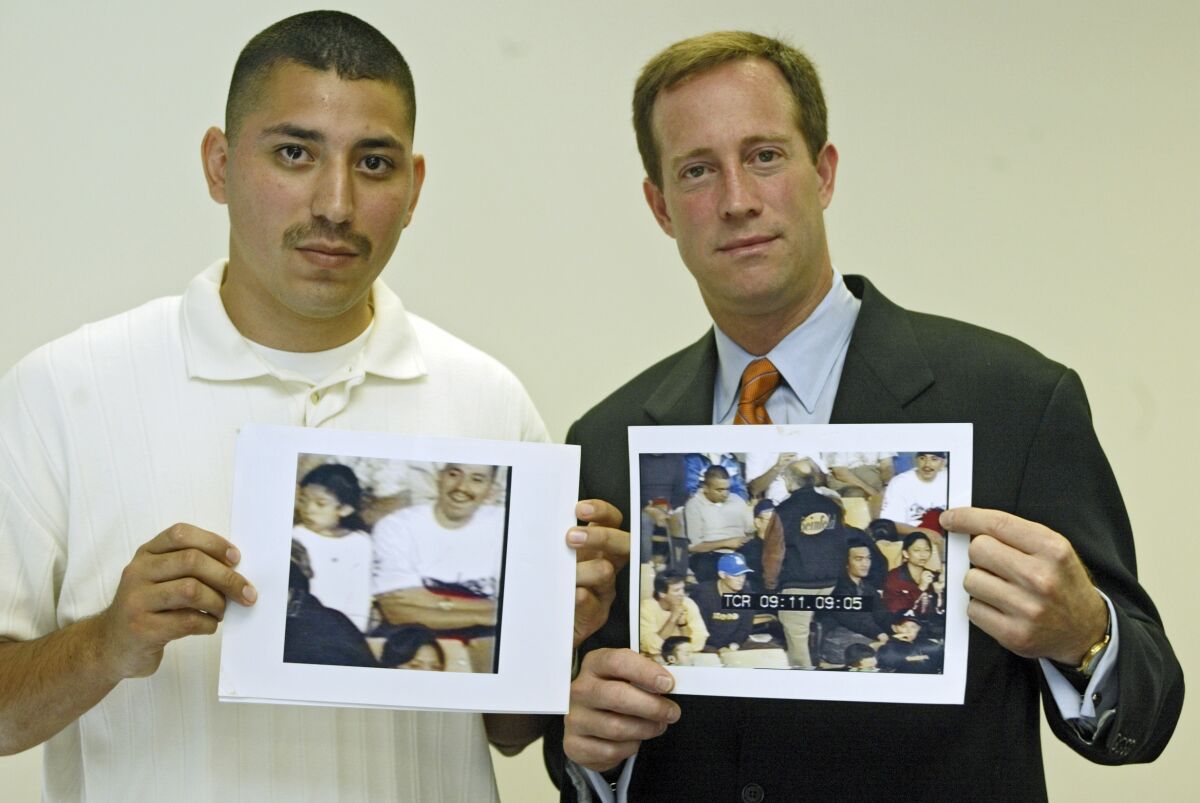 Juan Catalan, left, and his attorney Todd Melnik hold photos of found video footage taken at Dodger Stadium