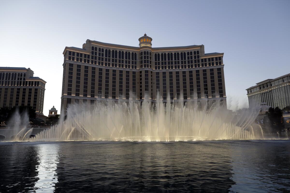 A wide array of arcing water fountains in a large pool in front of a Las Vegas hotel
