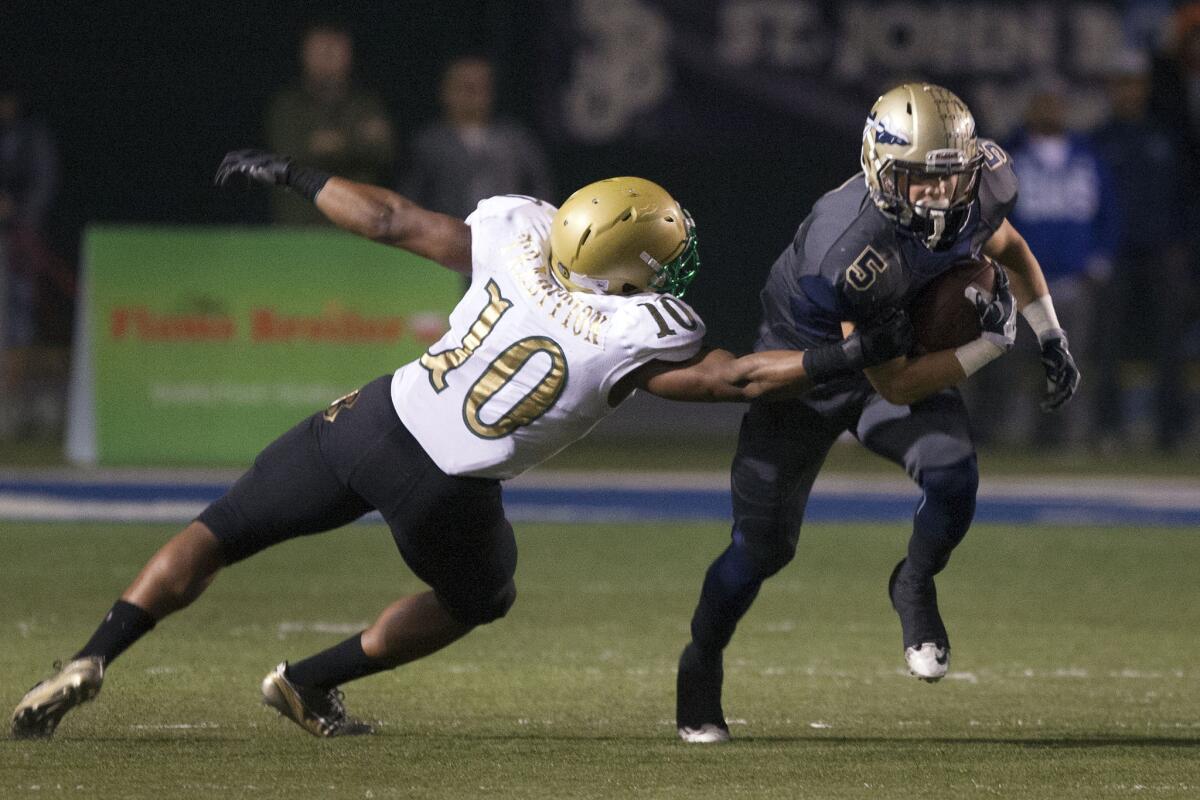 St. John Bosco running back Sean McGrew tries to evade Poly linebacker James Brooks Jr. in the first half.