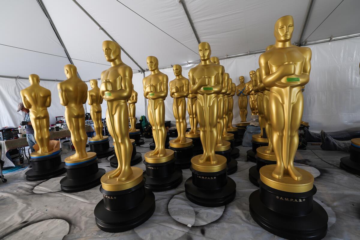 A collection of human-size Oscar statues in a white tent