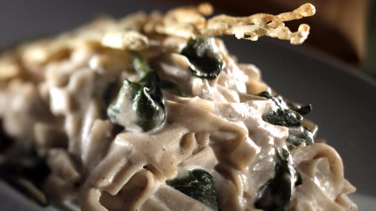 Fettuccine Alfredo with sauteed spinach and cheese crisps is both vegan and gluten-free.