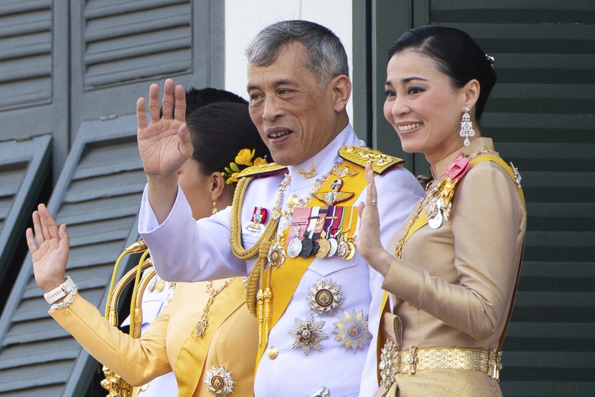 King Maha Vajiralongkorn and Queen Suthida wave to an audience