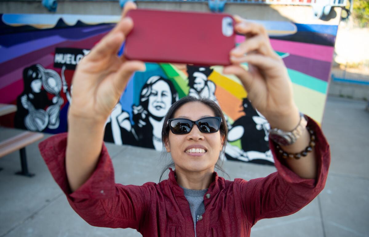 Neighbor Jane Yamashiro takes a selfie in front of a mural depicting presidential candidate Kamala Harris on a wall at Thousand Oaks Elementary School in Berkeley on June 29.
