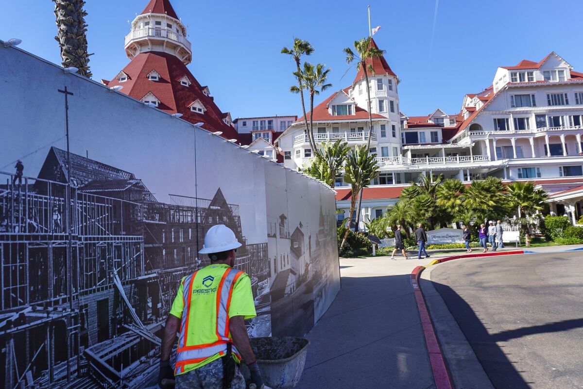 Hayne Palmour IV  U-T A construction worker walks past fencing that pictures the original Hotel del Coronado. Renovation work could force as many as 160 layoffs.