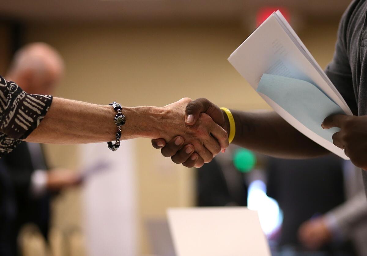 A job-seeker shakes hands with a recruiter during the HIREvent in Emeryville, Calif. The U.S. Labor Department says the number of people filing for first-time unemployment benefits was down 24,000 from the previous week.