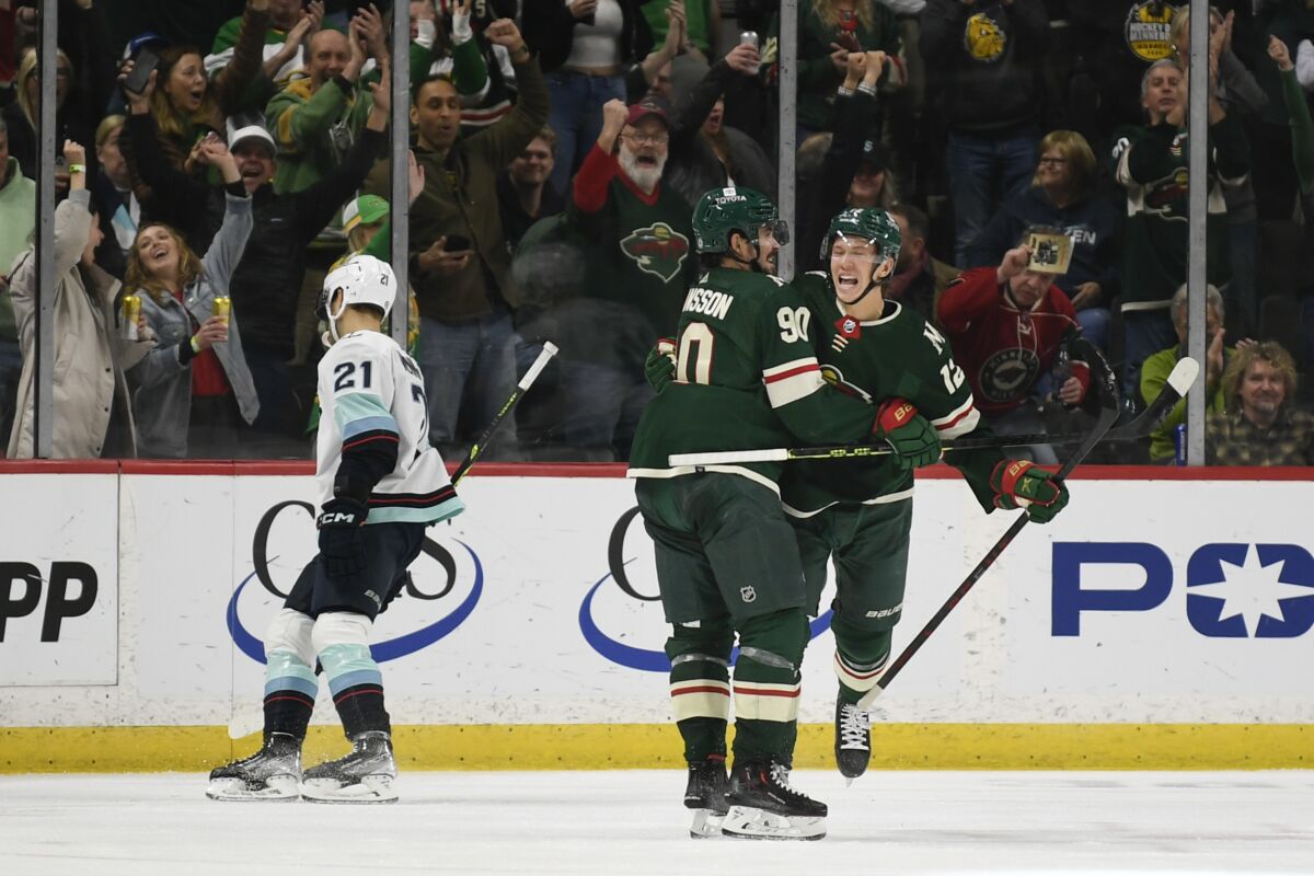 Minnesota Wild left wing Matt Boldy, right, celebrates with left wing Marcus Johansson after scoring a goal as Seattle Kraken center Alex Wennberg (21) skates away during the second period of an NHL hockey game Monday, March 27, 2023, in St. Paul, Minn. (AP Photo/Craig Lassig)