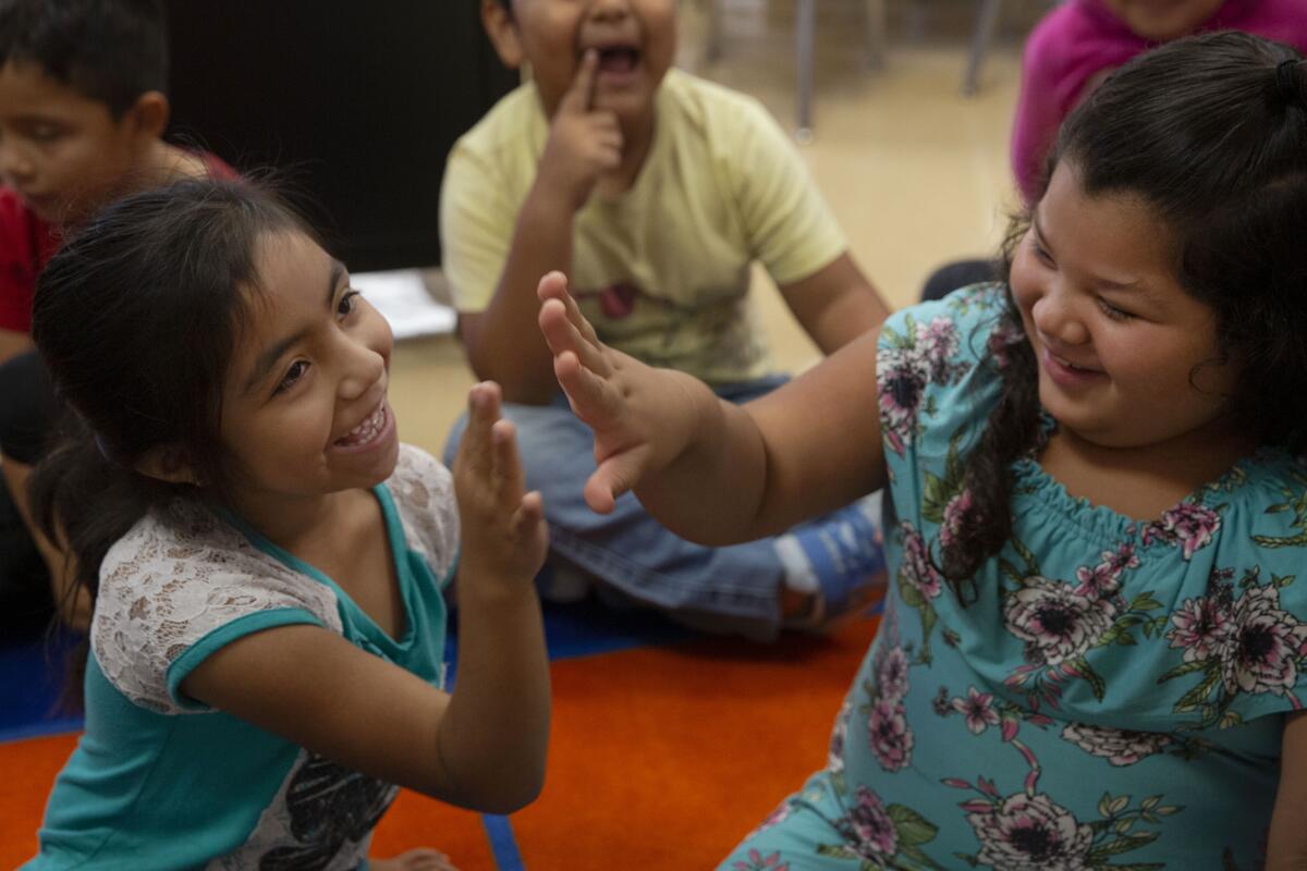 First-grade students at Esperanza Elementary School in Los Angeles high-five each other during class in 2019.