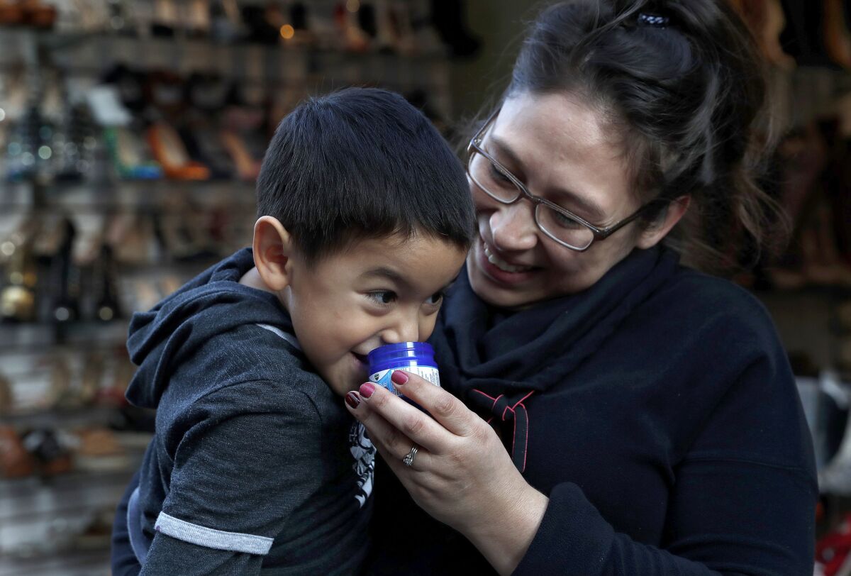 Emmanuel Juarez, 4, and his mother, Esmeralda Orozco, visiting from Oregon, smell a jar of Vicks VapoRub at the Santee Alley in downtown Los Angeles. (Mel Melcon / Los Angeles Times)
