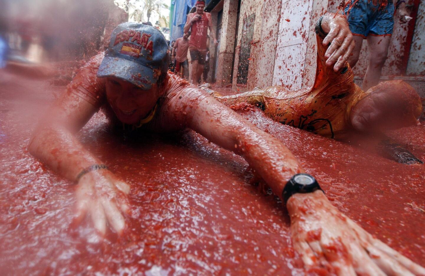 Two men fall to the ground as they participate in the traditional annual tomato fight, known as "Tomatina," in Bunol, Spain, on Aug. 31, 2016.