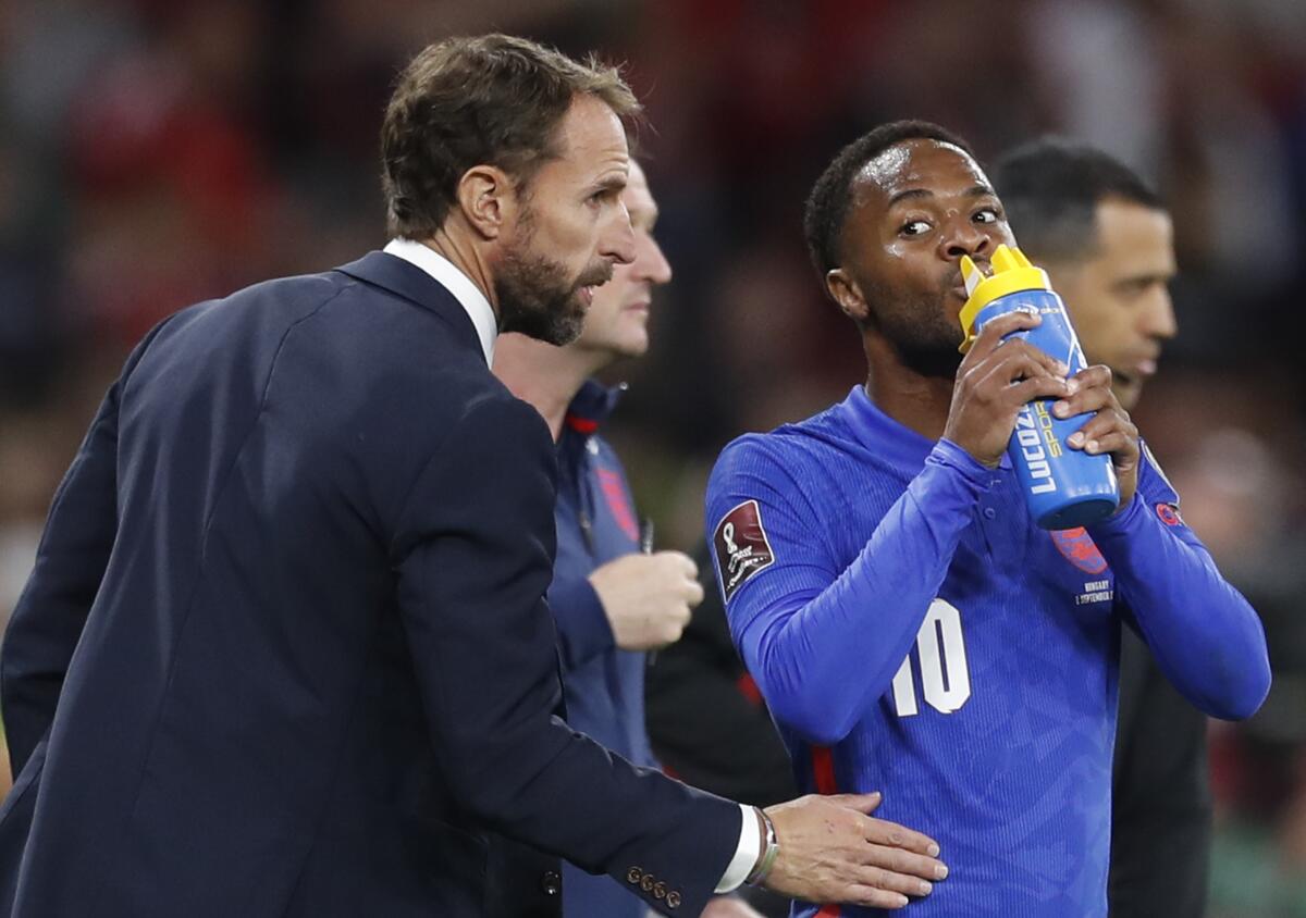 England's manager Gareth Southgate talks to Raheem Sterling during the World Cup 2022 group I qualifying soccer match between Hungary and England at the Ferenc Puskas stadium in Budapest, Hungary, Thursday, Sept. 2, 2021. (AP Photo/Laszlo Balogh)
