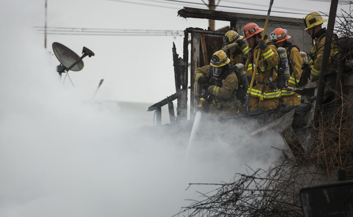 Firefighters spray water from the roof of a Maywood warehouse where an explosive fire burned earlier this month.