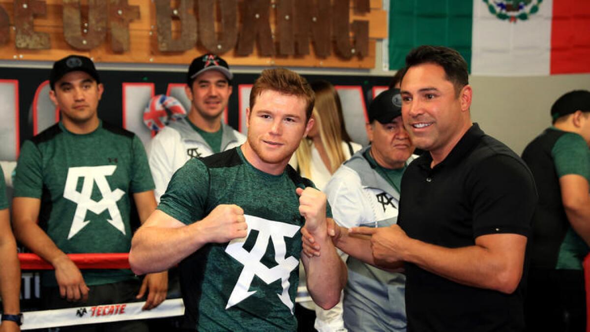 Saúl "Canelo" Álvarez (izq.) posa con Oscar De la Hoya durante un entrenamiento ante medios de comunicación el 25 de abril en el Gimnasio House of Boxing en San Diego.