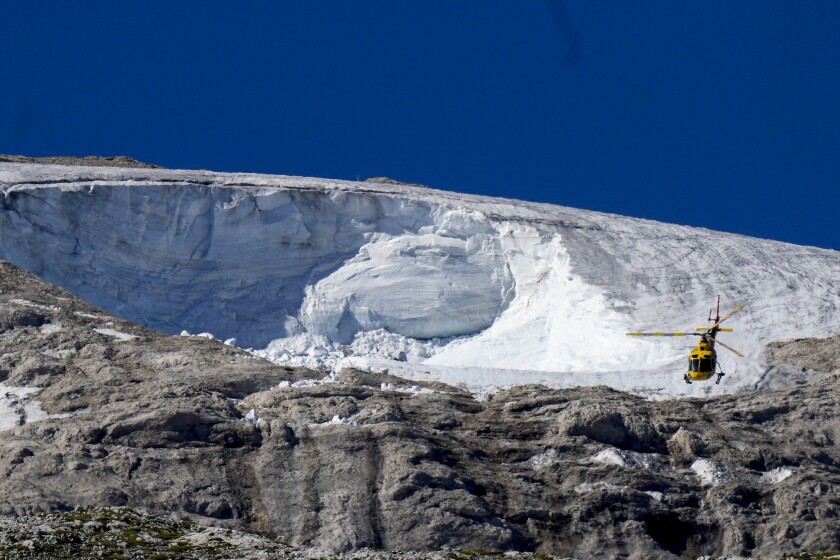 A rescue helicopter flies over the Punta Rocca glacier near Canazei, in the Italian Alps in northern Italy, Wednesday, July 6, 2022, where an avalanche broke loose on Sunday, sending tons of ice, snow, and rocks onto hikers. (AP Photo/Luca Bruno)