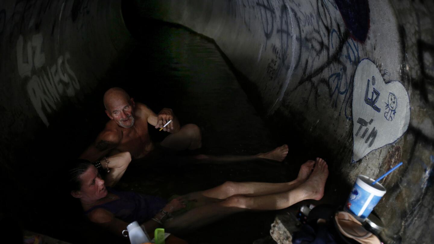 Liz Gonzales, 50, bottom, and Tim Wilburn, top, bathe together in the "spa," a culvert near the Second Street bridge.