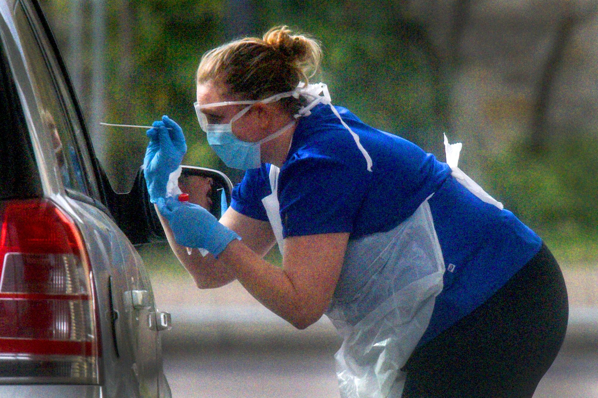 ENGLAND: A nurse prepares to swab a driver at a drive- through COVID-19 testing station in Chessington on March 28.