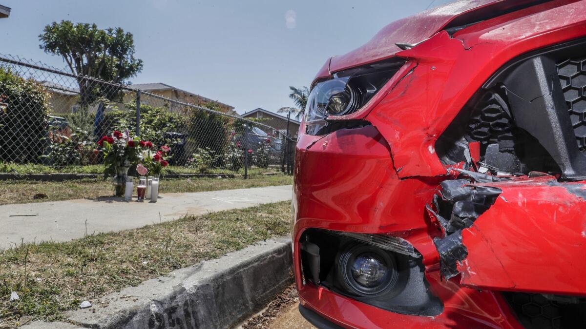 A makeshift memorial sits near where a woman was killed in a street-racing crash. The red Mustang, parked along the curb, was struck during the collision.