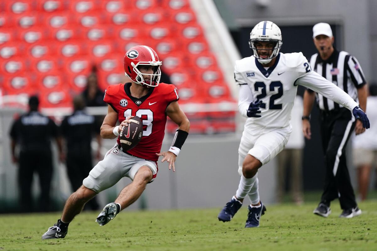 Georgia quarterback Stetson Bennett (13) eludes Samford linebacker Brayden DeVault-Smith (22) as he looks for an open receiver during the first half of an NCAA college football game, Saturday, Sept. 10, 2022 in Athens, Ga. (AP Photo/John Bazemore)