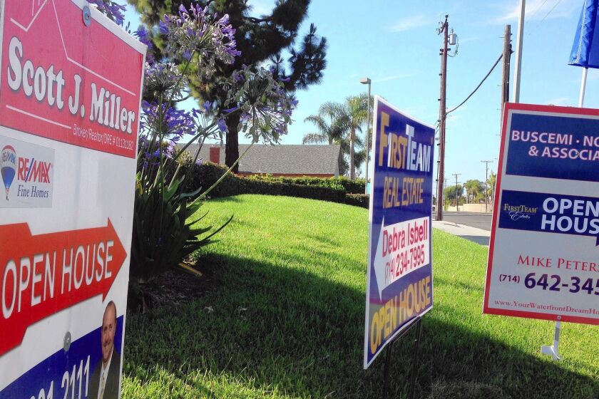 Signs direct home shoppers to open houses in Huntington Beach in June 2014.