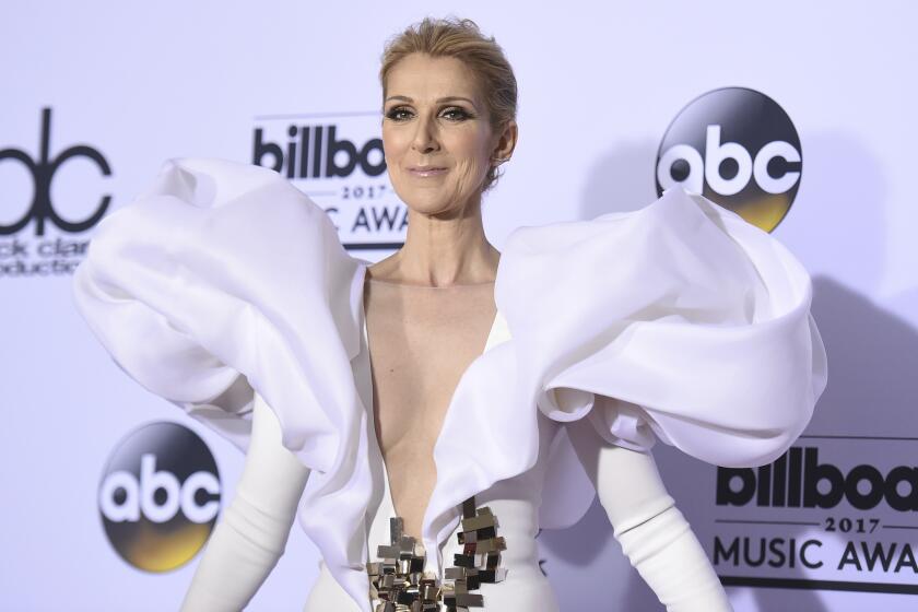 Celine Dion poses in a white puff-sleeved gown