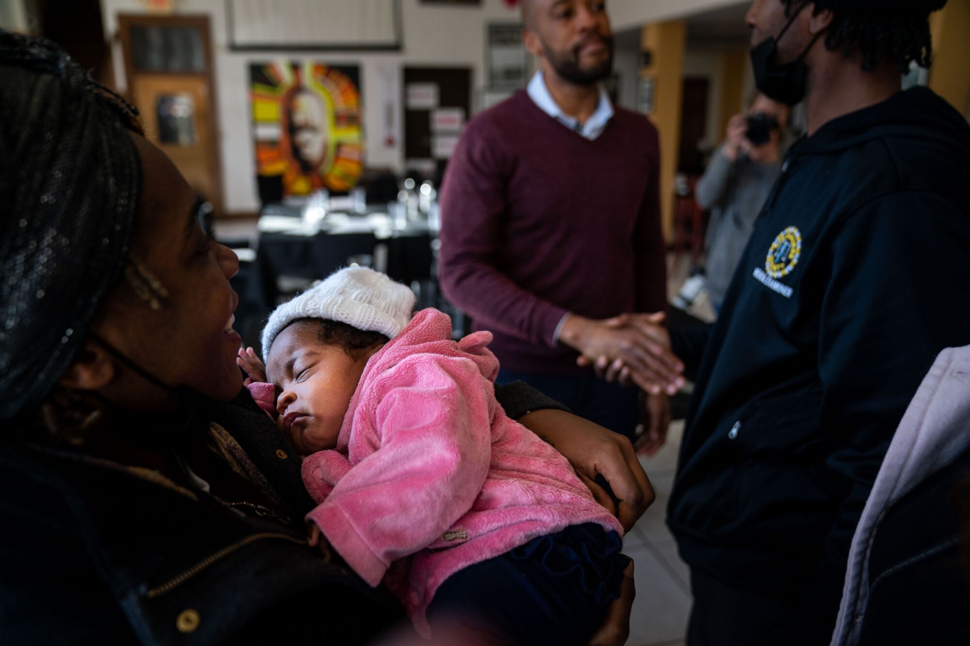 Makoria Morrow holds her 2-month-old daughter as Joe Louis Gordon shakes hands with Mandela Barnes