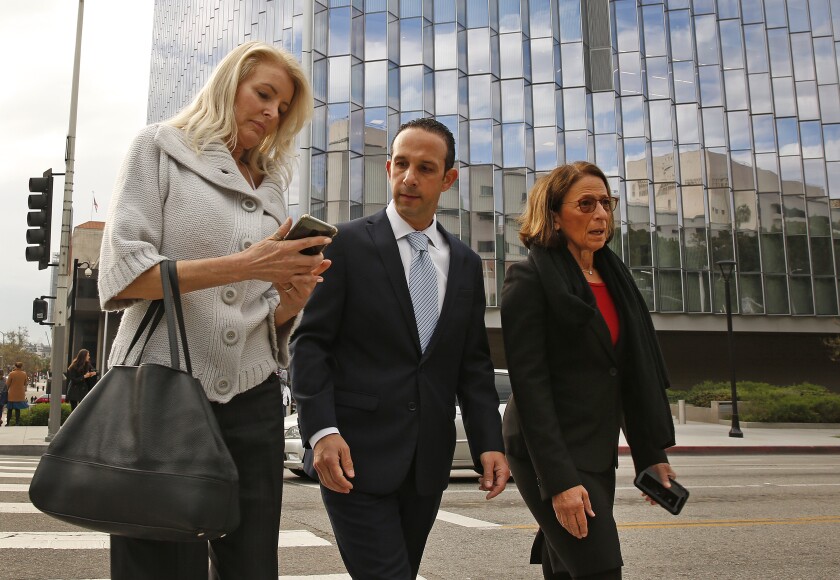 Mitchell Englander walks across the street in downtown last year flanked by his wife and his lead attorney.