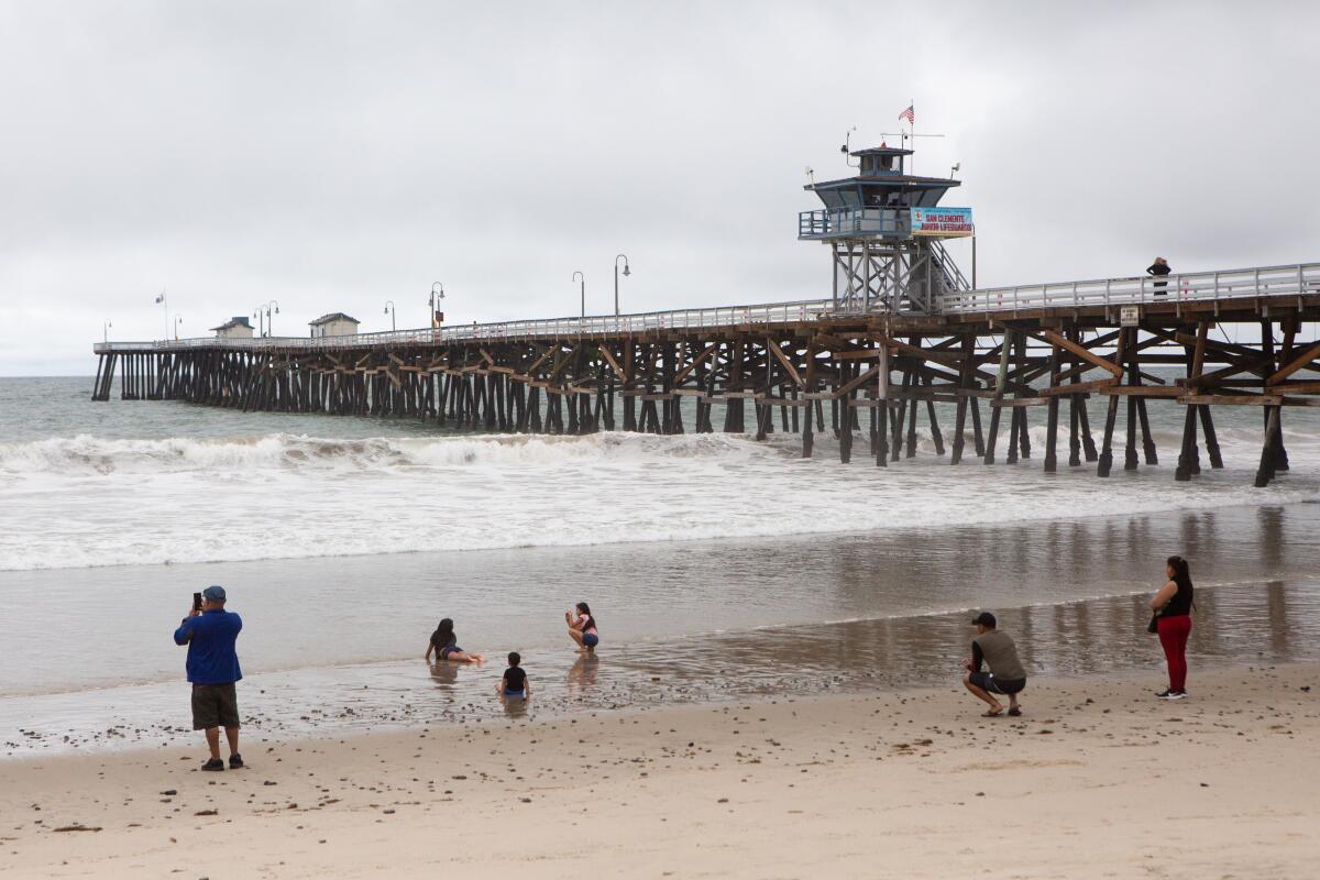 Families practice social distancing while playing in the water and sand near the San Clemente Pier on May 18.