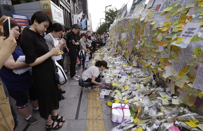 A woman places flowers for a South Korean woman who was stabbed to death at an exit of Gangham subway station in Seoul, South Korea, on Saturday, May 21.