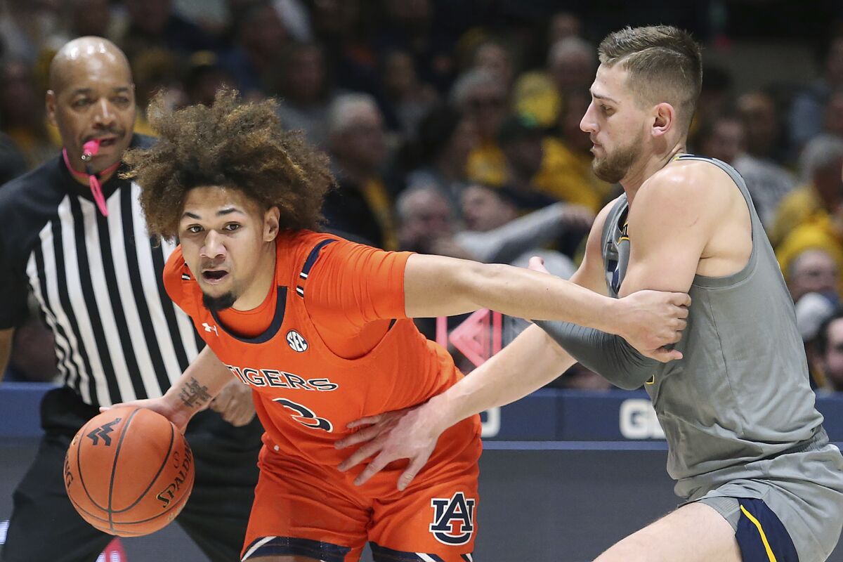 Auburn guard Tre Donaldson (3) is defended by West Virginia guard Erik Stevenson during the first half of an NCAA college basketball game on Saturday, Jan. 28, 2023, in Morgantown, W.Va. (AP Photo/Kathleen Batten)