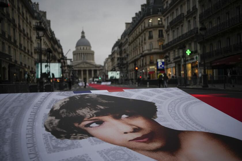 Pictures of Josephine Baker and a red carpet lead to the Pantheon monument, rear, in Paris, France, Tuesday, Nov. 30, 2021 , where Baker is to symbolically be inducted, becoming the first Black woman to receive France's highest honor. A coffin carrying soils from the U.S., France and Monaco will be deposited inside the Pantheon. Her body will stay in Monaco at the request of her family. (AP Photo/Christophe Ena)