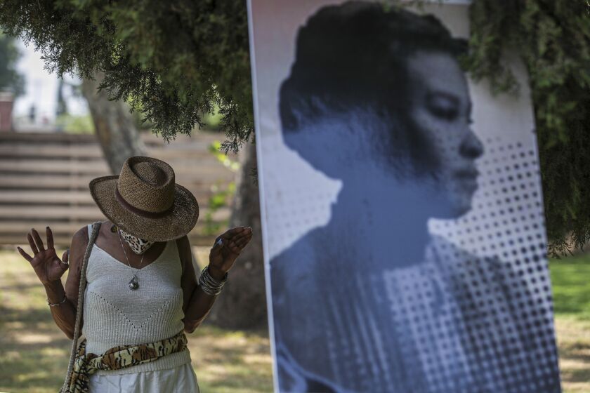 Altadena, CA - June 19: Zenobia Millet, left, standing next to the photo of anti-slavery and civil rights activist Ellen Garrison Clark offers her respect at a ceremony held to unveil headstone for the unmarked grave of Clark at Mountain View Cemetery on Saturday, June 19, 2021 in Altadena, CA. (Irfan Khan / Los Angeles Times)