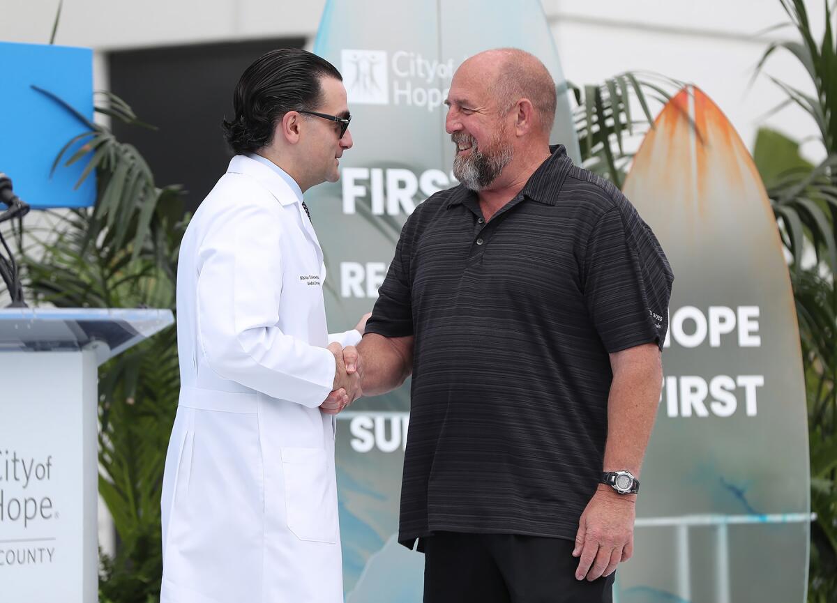 Huntington Beach Mayor Pro Tem Pat Burns, right, shakes hands with oncologist Nishan Tchekmedyian.