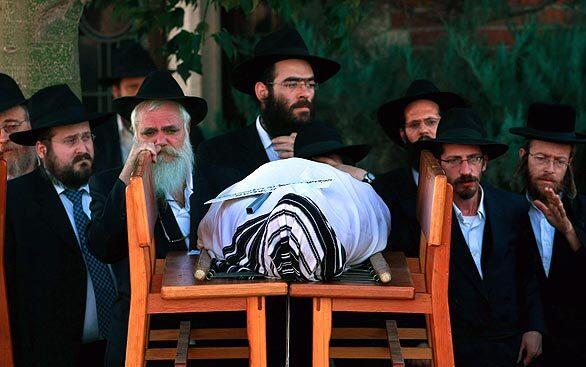 Ultra-Orthodox Jewish mourners near Tel Aviv pray behind the shroud-covered body of Rabbi Gavriel Noach Holtzberg during the funeral for the Chabad Lubavitch House emissary and his wife, Rivka. They were killed in the terror attacks in Mumbai last week; the couple's 2-year-old son, Moshe, survived.