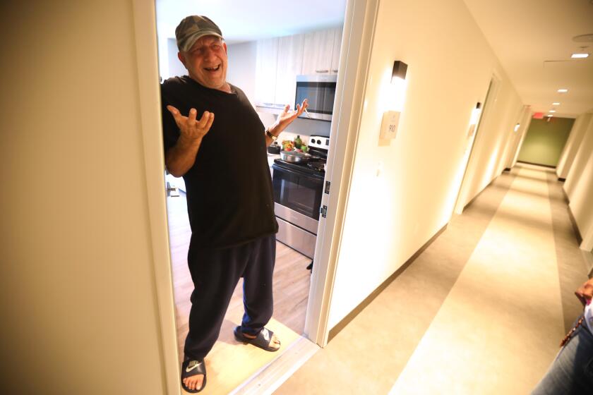 LOS ANGELES, CA - AUGUST 6, 2024 - Mike Juma, 64, welcomes a guest to his room at the new Weingart Tower in Skid Row in Los Angeles on August 6, 2024. Juma is among the hundreds of homeless people who have been moved into permanent housing as part of a L.A. County Dept. of Health Services Skid Row Action Plan, a $280-million county initiative aimed at improving life in the downtrodden neighborhood by addressing the need for more interim and permanent housing, behavioral health and substance use treatment, among other services. (Genaro Molina/Los Angeles Times)