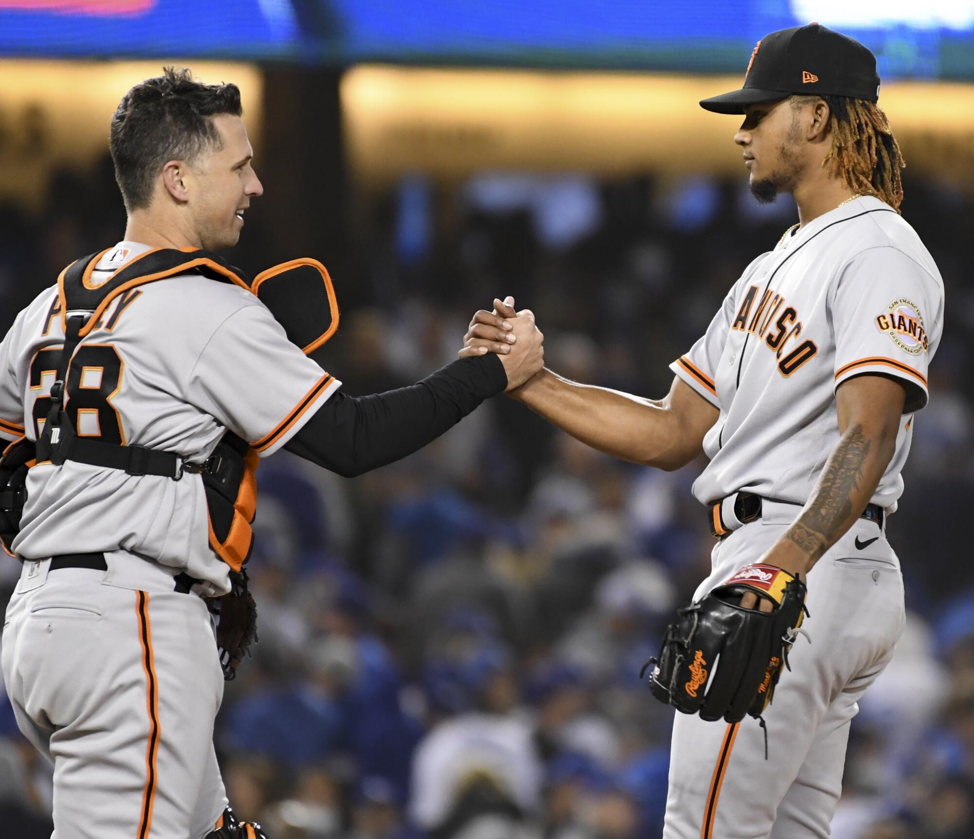 San Francisco Giants relief pitcher Camilo Doval, right, celebrates with Buster Posey after game three