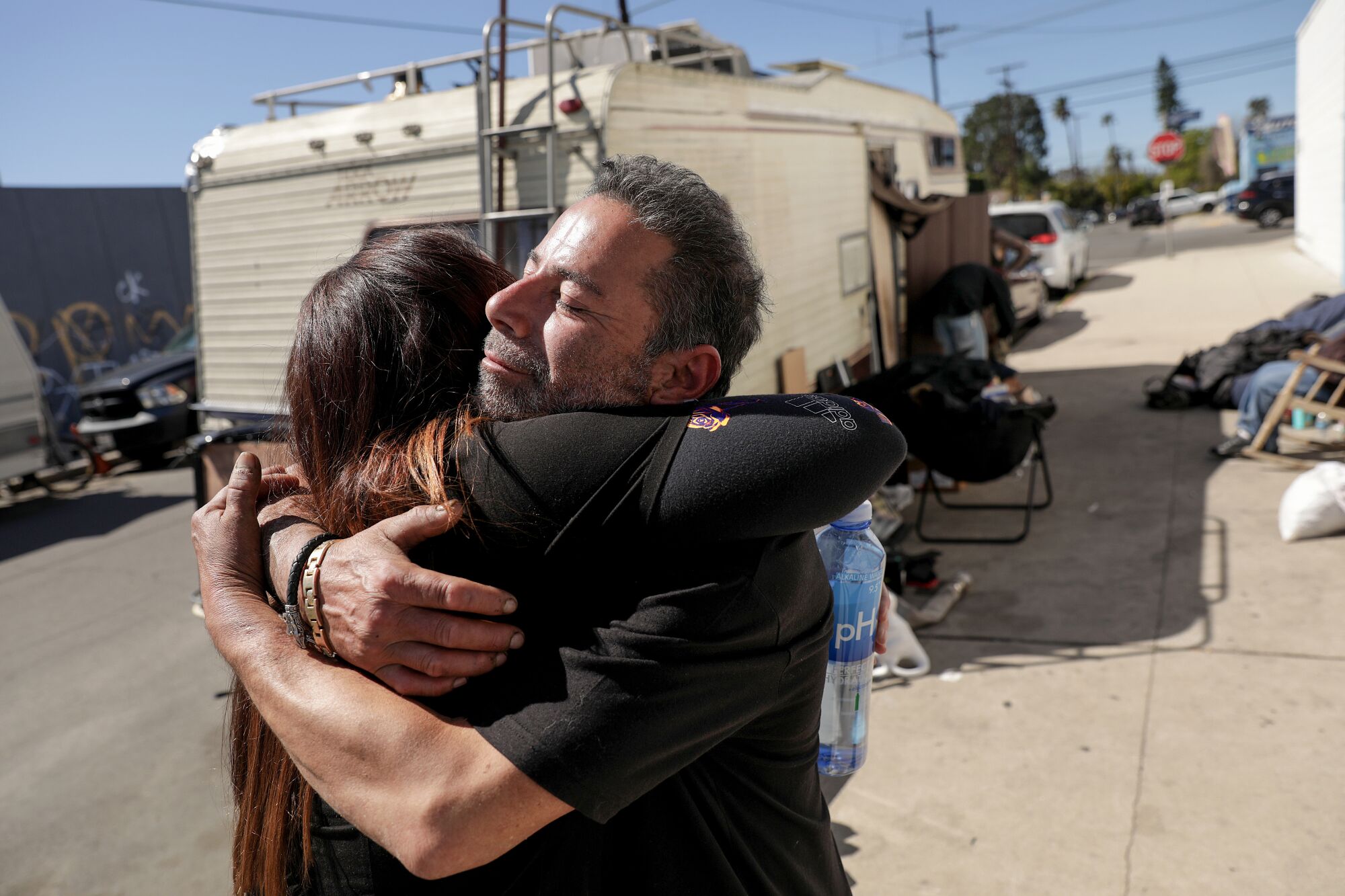 Two people hug each other outdoors.