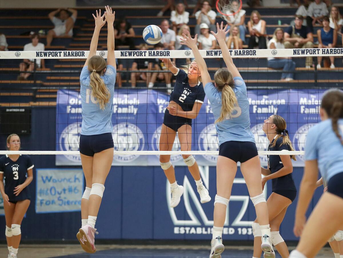 Newport Harbor's Ella Olson finds a gap for a kill between Molly Machoskie and Savi Dennis.