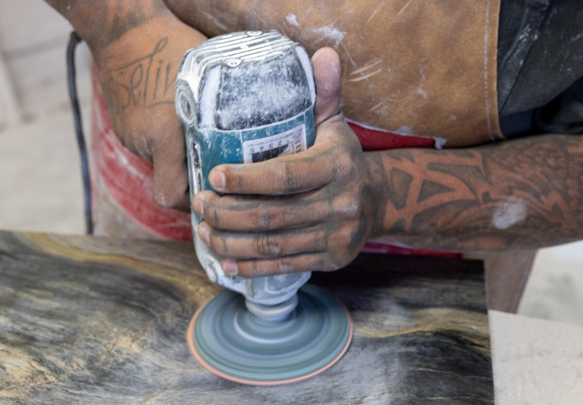 A worker polishes a countertop surface using a power tool