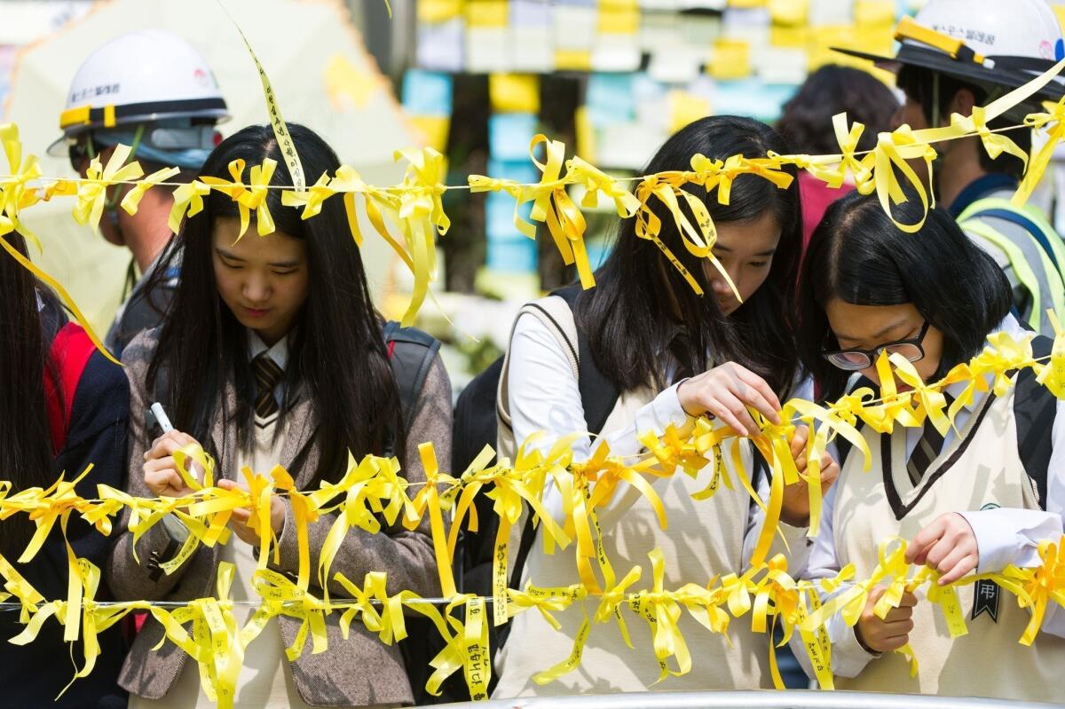 Students tie yellow ribbons for the missing ferry passengers near the main gate of Danwon High School.