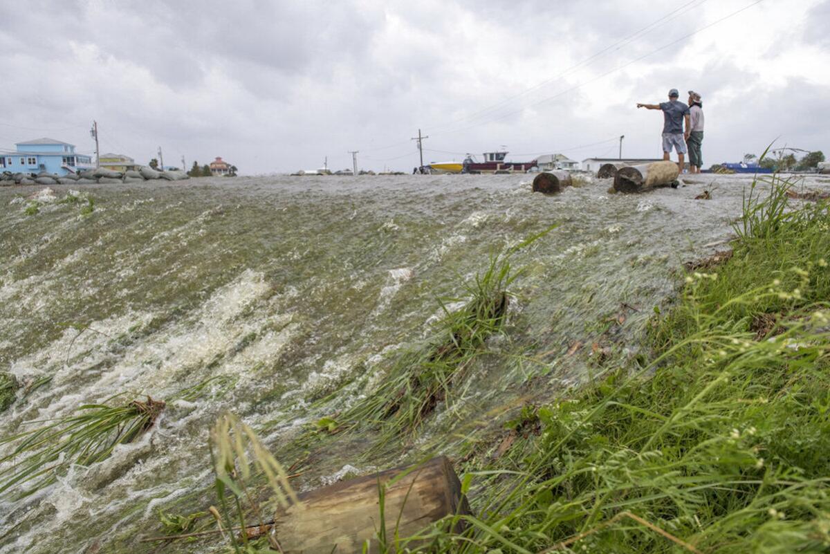 Dos personas miran el agua de mar que superó un dique en el distrito de Plaquemines, al sur de Nueva Orleans, mientras el huracán Barry tocaba tierra en la costa.