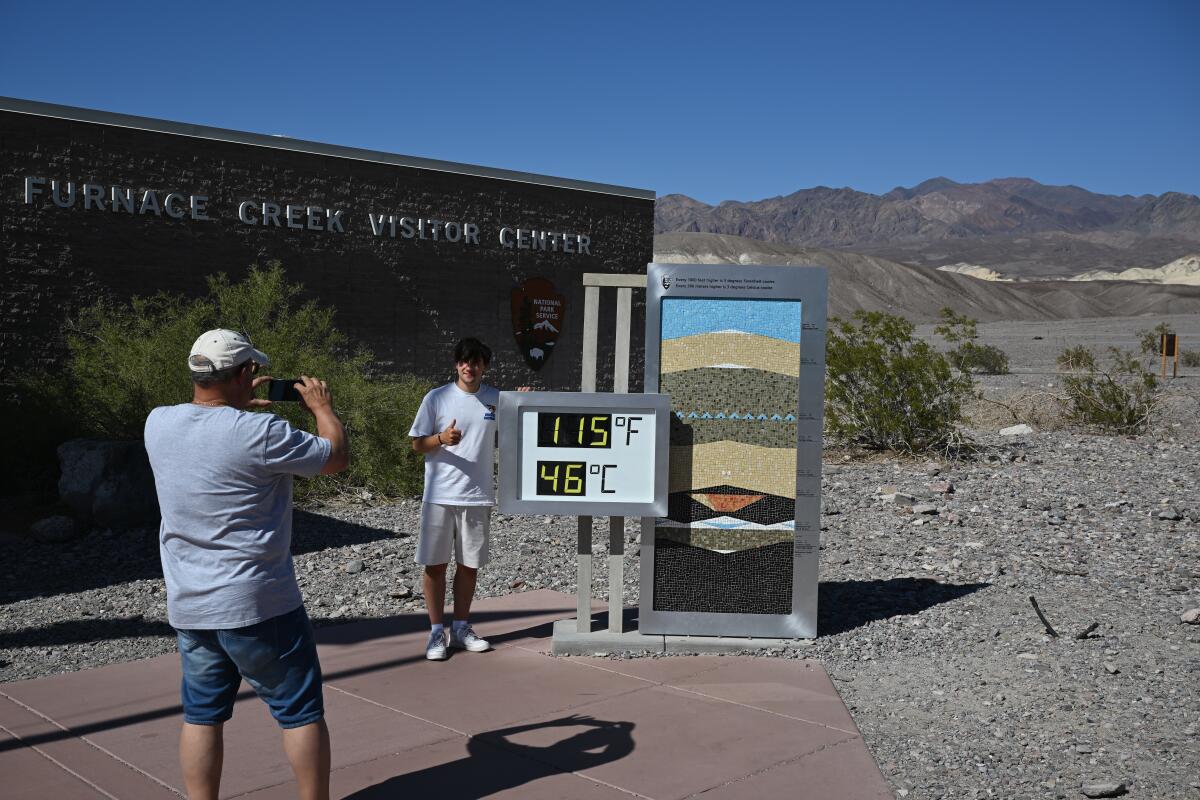 A visitor poses for a photo with the thermometer at the Furnace Creek Visitor Center in Death Valley on Sunday.