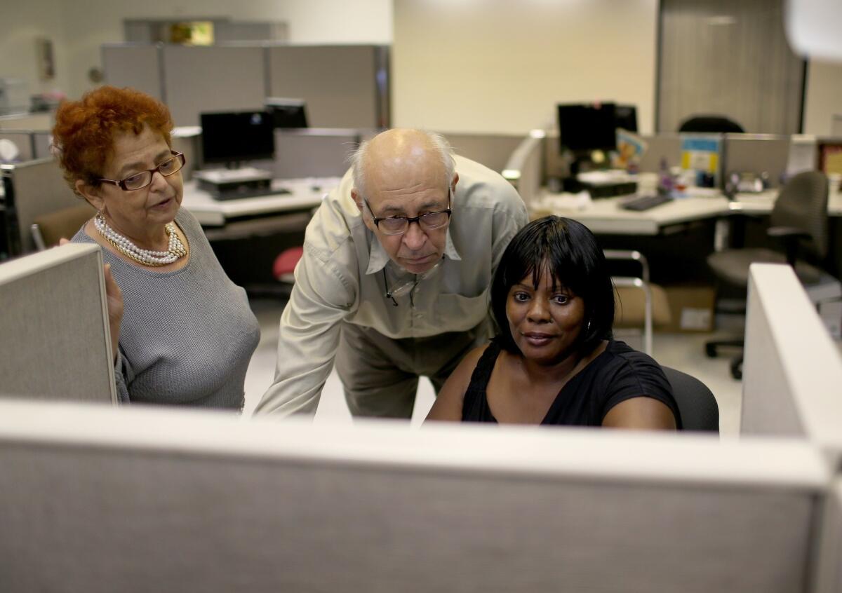 Eva Totfalusi, left, and Aladar Totfalusi help Betty Watson, right, as she looks for job opportunities on a computer at CareerSource Florida in Miami on Aug. 1.
