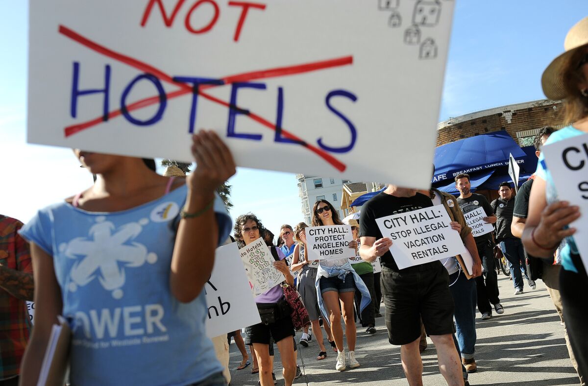 Dozens of Venice residents and advocates rally on the Venice Boardwalk on Aug. 3, 2015, to call on the Los Angeles City Council to regulate short-term rentals, such as those from Airbnb.