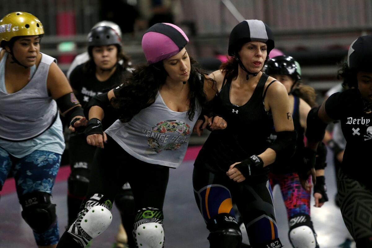 Rachel Garcia ("Sugar"), center left, of Beach Cities, bumps Amy Gantvoort ("DoomsDaisy") of Derby Dolls, an all-female, banked-track roller derby league, during a scrimmage in Los Angeles on Jan. 4.