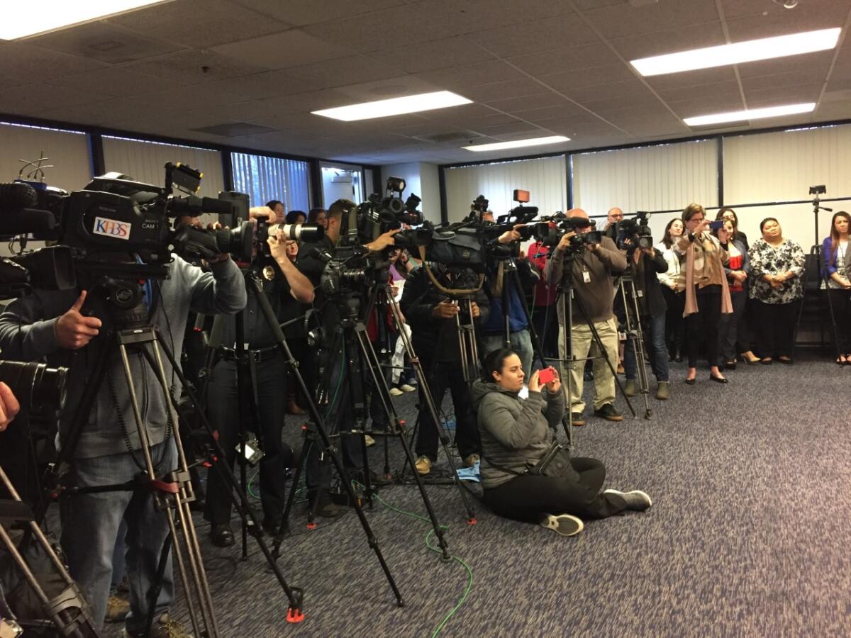 Alexandra Mendoza (seated) takes a photo at a San Diego Police Department headquarters press conference in 2018.