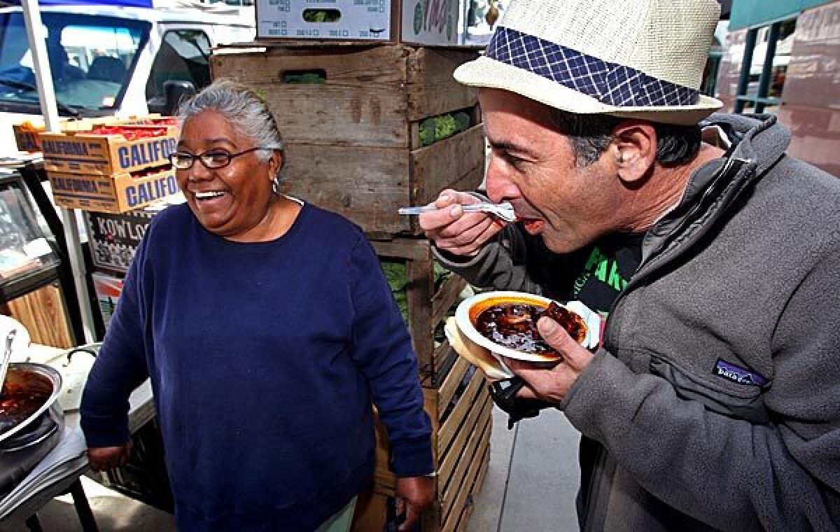 Sotera Jaime of Jaime Farms serves puerco con chile negro to Alex Weiser at the Santa Monica farmers market.