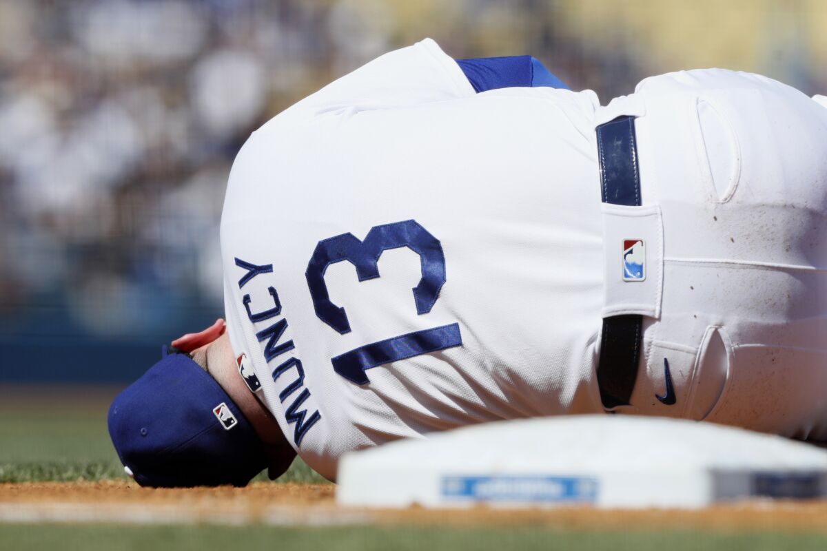 Los Angeles Dodgers first baseman Max Muncy lies on the ground after colliding with Milwaukee Brewers' Jace Peterson on a play at first base on an infield ground ball during the third inning of a baseball game in Los Angeles, Sunday, Oct. 3, 2021. Peterson was ruled out at first for running inside the base line. (AP Photo/Alex Gallardo)