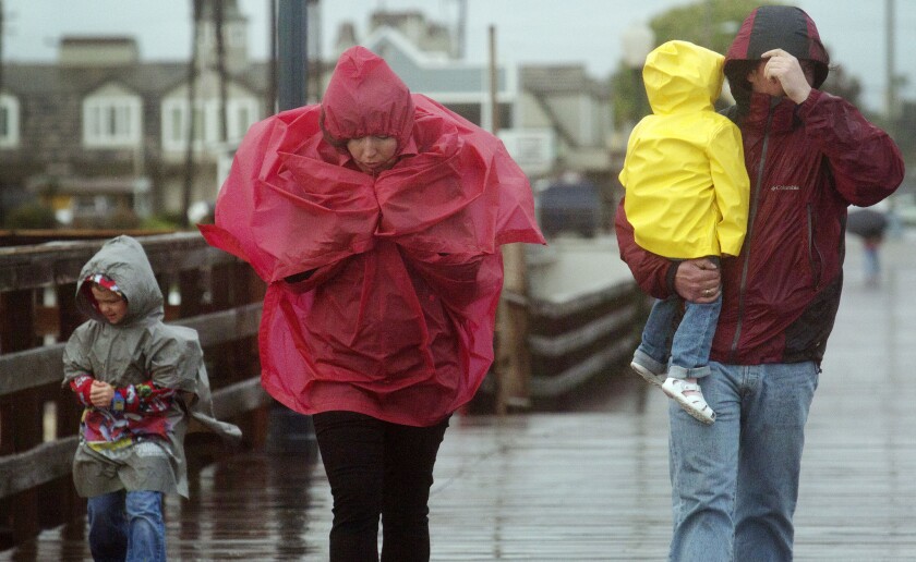 Arseniy Kalistratoe, 6, from left; his mother, Julia; his sister, Uliana, 2; and his father, Andre, use their rain gear as they stroll on the pier at Seal Beach on Feb 28.