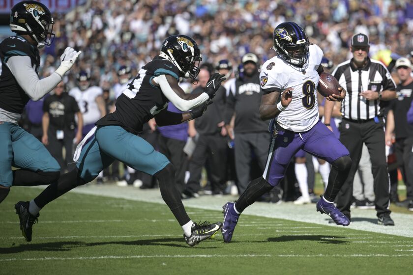 Baltimore Ravens quarterback Lamar Jackson (8) scrambles for yardage against Jacksonville Jaguars linebacker Devin Lloyd (33) during the first half of an NFL football game, Sunday, Nov. 27, 2022, in Jacksonville, Fla. (AP Photo/Phelan M. Ebenhack)