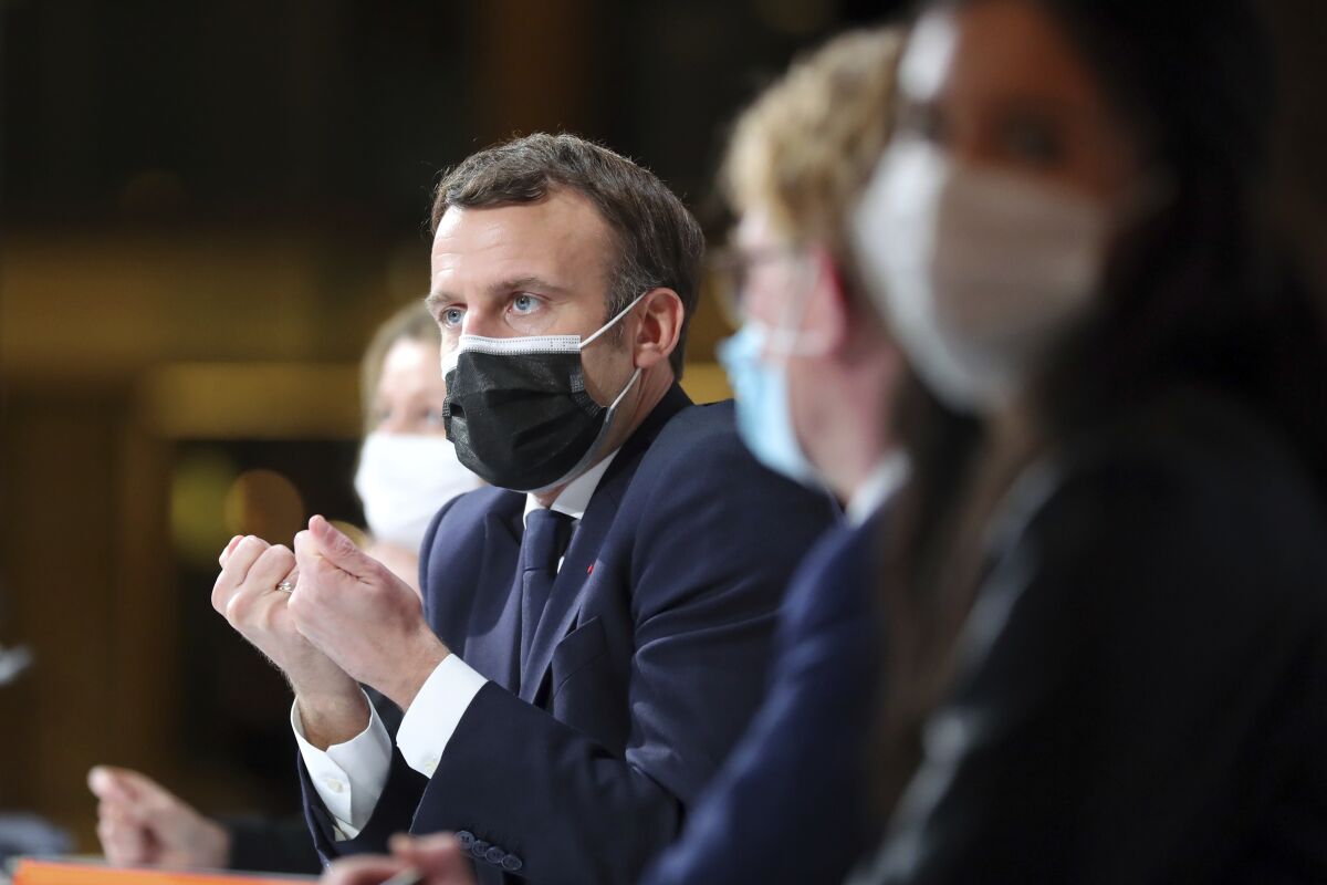 French President Emmanuel Macron in a mask next to other masked officials